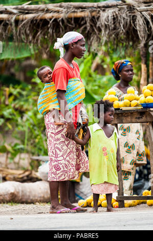 ACCRA, GHANA - MARCH 2, 2012: Unidentified Ghanaian woman with her child on her back at the market in the street in Ghana. People of Ghana suffer of p Stock Photo