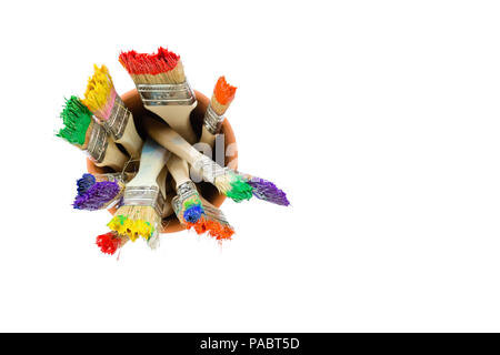 Set of paint brushes with colorful vibrant rainbow-colored paint on the bristles standing upright in a jar or container viewed from above on white wit Stock Photo