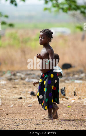 ACCRA, GHANA - MARCH 6, 2012: Unidentified Ghanaian girl walks with her little sister in the street in Ghana. Children of Ghana suffer of poverty due  Stock Photo