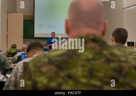 Scott Warren (standing), a Houston, Texas police officer and member of the Federal Emergency Management Agency training team, instructs servicemembers from the Massachusetts Army and Air National Guard as well as Canadian army reserve soldiers during the first day of civil disturbance response training at the Devens Reserve Forces Training Area, Mass., March 4, 2016.  Members of the MAANG have an established partnership program with the Canadian reserve soldiers and participate in joint training with them regularly, but this is the first training of this nature involving both forces. The train Stock Photo