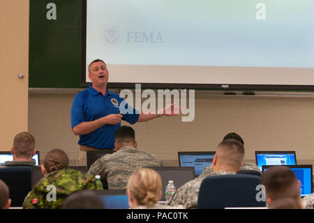 Scott Warren (standing), a Houston, Texas police officer and member of the Federal Emergency Management Agency training team, instructs servicemembers from the Massachusetts Army and Air National Guard as well as Canadian army reserve soldiers during the first day of civil disturbance response training at the Devens Reserve Forces Training Area, Mass., March 4, 2016.  Members of the MAANG have an established partnership program with the Canadian reserve soldiers and participate in joint training with them regularly, but this is the first training of this nature involving both forces. The train Stock Photo