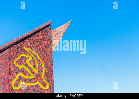 Old communist monument with the symbol of the USSR Sickle and hammer against the blue sky, with copy space. Stock Photo