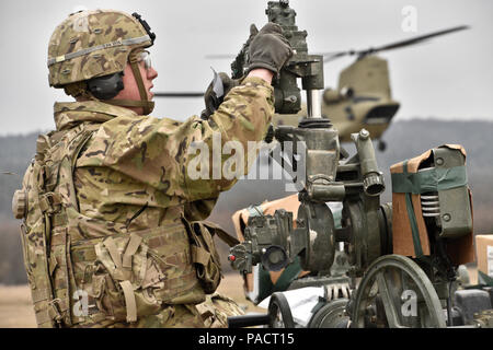 Spc. Austin Dubiser, a cannon crew member assigned to Archer Battery, Field Artillery Squadron, 2nd Cavalry Regiment, helps his team clear and prepare their unit's M777 Howitzer after they, along with their equipment, were transferred from one firing position to another via a CH-47 Chinook helicopter from the 12th Combat Aviation Brigade (Helicopter Detachment) during their unit's sling load operations conducted at the Grafenwoehr Training Area, located near Rose Barracks, Germany, March 23, 2016. The purpose of this event was to conduct Artillery Table II training while helping to establish w Stock Photo