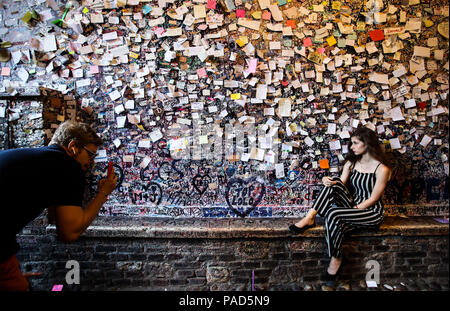 Verona, Italy. 20th July, 2018. A woman poses for photos with the graffiti wall of Juliet's House in Verona, Italy, July 20, 2018. Juliet's House, considered as the home of Juliet, heroine of Shakespeare's famous play 'Romeo and Juliet', is one of the well-known tourist spots in Verona. Verona is located in north Italy's Veneto. As one of the main tourist destinations in north Italy, the city has artistic heritages, annual fairs, shows, and operas. It was listed as a UNESCO world heritage site in 2000 for its historical buildings. Credit: Jin Yu/Xinhua/Alamy Live News Stock Photo