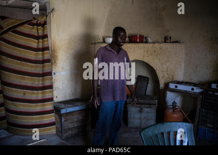 Nijar, Spain. 21st July, 2018. 21.07.2018, Spain, Almería, Nijar: A migrant stands at a kitchen he shares with 25 other people at a permanet settlement near Nijar, Almeria, Spain. Over 50 african undocumented migrants live in poor conditions while hoping to get some work on the nearby plantations. Credit: Javier Fergo/dpa/Alamy Live News Stock Photo