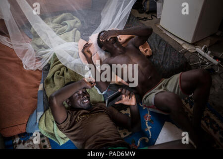 Nijar, Spain. 21st July, 2018. 21.07.2018, Spain, Almería, Nijar: Two migrants from Ghana lay at their hut, shared with 2 others, at a permanet settlement near Nijar, Almeria, Spain, where over 50 african undocumented migrants live in poor conditions while hoping to get some work on the nearby plantations. They travelled from Italy, after spending over a year at Libya suffering tortures and then travelling by dinghy on the Mediterranean. Credit: Javier Fergo/dpa/Alamy Live News Stock Photo