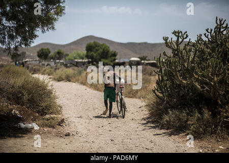 Nijar, Spain. 21st July, 2018. 21.07.2018, Spain, Almería, Nijar: A migrant carries a water tank to his hut in a permanet settlement near Nijar, Almeria, Spain; Over 50 african undocumented migrants live in poor conditions while hoping to get some work on the nearby plantations. Credit: Javier Fergo/dpa/Alamy Live News Stock Photo