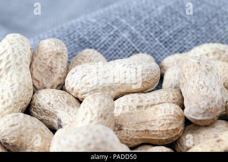 old cracked and in shell nuts peanuts lying together on a linen tablecloth, closeup Stock Photo
