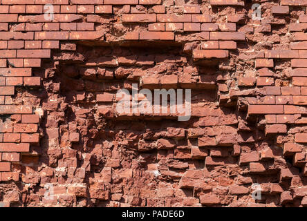 part of the destroyed from the pothole from the beat of the shell of the building wall, made long ago from the red brick, the ruins of the fortress Stock Photo