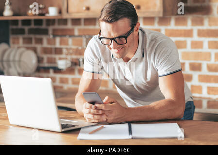 Delighted nice man using his smartphone Stock Photo