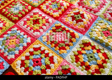 Brightly coloured granny square woollen baby blanket, traditional hand made crochet home handicraft Stock Photo