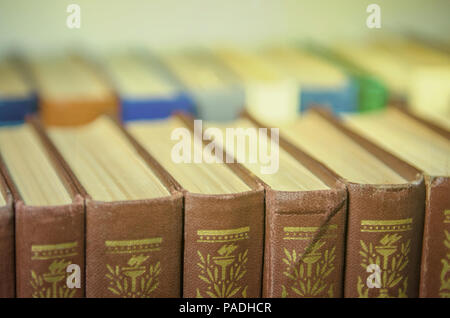 a stack of colorful books on the shelf in a library or a room close-up Stock Photo