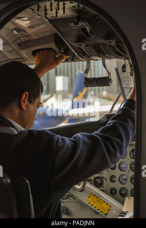 Pilot operating the throttle control of a Twin Otter float plane on its ...