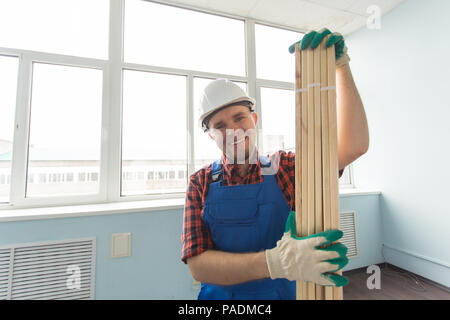 Closeup portrait of handsome male builder with wooden boards, wearing gloves. Stock Photo