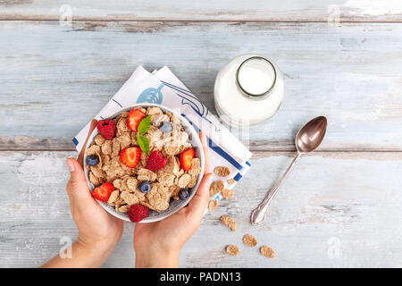 Young woman with bowl of tasty corn-flakes with healthy berries from above. Delecious breakfast. Stock Photo