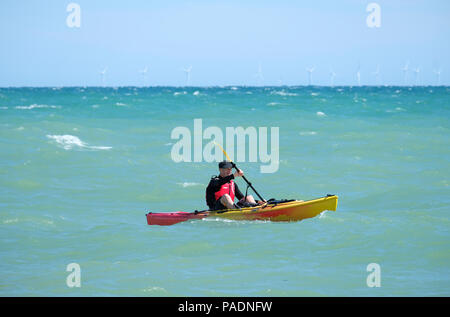 Man wearing life jacket paddling his Kayak in choppy seas off the coast of East Preston, West Sussex, UK. Direction East to West. Stock Photo