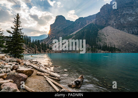 Sunrise with turquoise waters of the Moraine lake with sin lit rocky mountains in Banff National Park of Canada in Valley of the ten peaks. Stock Photo