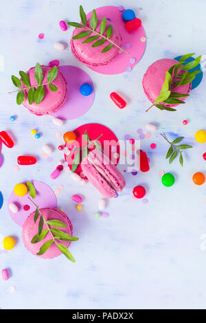 Macaroon cookies on a colorful background with confetti. Vibrant party concept with copy space. Pink and purple palette flat lay. Stock Photo
