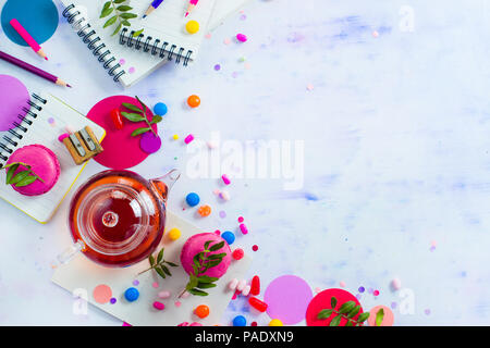Glass teapot header with candies and confetti on a light background with copy space. Pink and purple palette still life. Vibrant tea party drinks flat Stock Photo