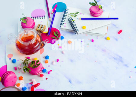 Glass teapot header with candies and confetti on a light background with copy space. Pink and purple palette still life. Vibrant tea party drinks conc Stock Photo