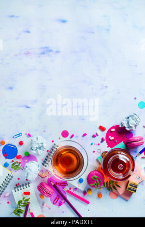 Tea party with a tiny glass teapot, candies, and confetti on a light background with copy space. Pink and purple palette still life. Vibrant drinks co Stock Photo