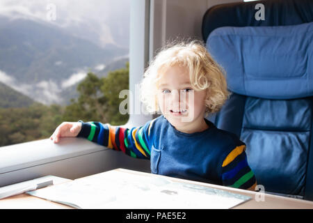 Child traveling by train. Little kid in a high speed express train on family vacation in Europe. Travel by railway. Children in railroad car. Kids in  Stock Photo