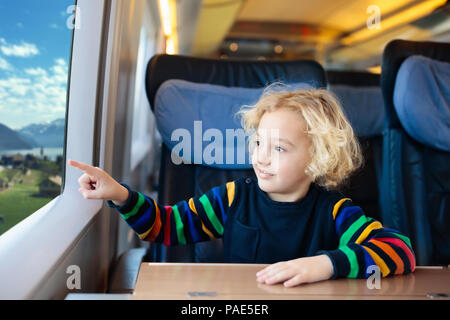 Child traveling by train. Little kid in a high speed express train on family vacation in Europe. Travel by railway. Children in railroad car. Kids in  Stock Photo