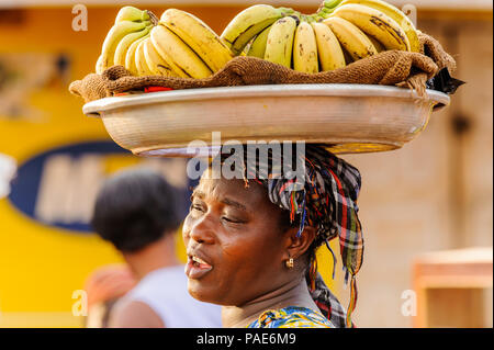 ACCRA, GHANA - MARCH 4, 2012: Unidentified Ghanaian woman carries bananas in the street in Ghana. People of Ghana suffer of poverty due to the unstabl Stock Photo