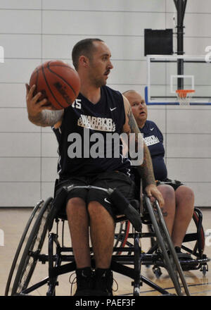 Team Navy/Coast Guard member retired Aviation Electrician's Mate Steven Davis of Turlock, Calif., takes command of the ball in a wheelchair basketball game against Team Air Force during the 2013 Warrior Games May 14. The Warrior Games includes competitions in archery, cycling, seated volleyball, shooting, swimming, track and field, and wheelchair basketball. The goal of the Warrior Games is not necessarily to identify the most skilled athletes, but rather to demonstrate the incredible potential of wounded warriors through competitive sports. More than 200 wounded, ill, or injured service membe Stock Photo