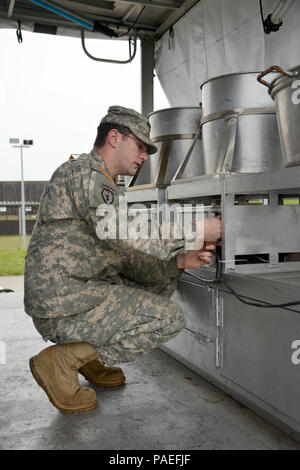 Cooks from the Wiesbaden Strong Teams Cafe Dining Facility (DFAC) brought a Mobile Kitchen Trailer (MKT) out to the Wackernheim Regional Range Facility on 30 March 2016 to feed the U.S. Army Europe Soldiers. Spc. Luke Wilson, a grill mechanic, checks the set up of the MKT used to prepare the meals which fed the Soldiers. After a long period of not being used, this is the first time the MKT has been set up to be used by the cooks for the Soldiers, it was a great opportunity for Ssg. King to teach the Soldiers how to get everything prepared, cleaned and put back together for another time and pla Stock Photo