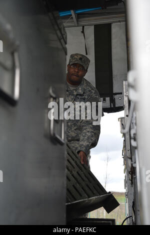 Ssg. Raymond King brings in the stairs for the Mobile Kitchen Trailer. Everything has it's place so that the trailer is compact and ready to go anywhere. Cooks from the Wiesbaden Strong Teams Cafe Dining Facility (DFAC) brought a Mobile Kitchen Trailer (MKT) out to the Wackernheim Regional Range Facility on 30 March 2016 to feed the U.S. Army Europe Soldiers. The three cooks, (NCO Ssg. Raymond King, and Spc. Michelle Santiago-Lopez, and Spc. Kallan Clements) and one grill mechanic (Spc. Luke Wilson), set up the MKT, prepared the meals, fed the Soldiers, cleaned the MKT, and broke down the trai Stock Photo