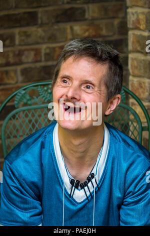 An older man with Downs Syndrome gives a huge smile.  The delight on his face shows off the fact that he has no more teeth.  The markers clipped to hi Stock Photo