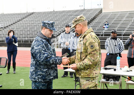 TACOMA, Wash. (Nov. 18, 2016) Cmdr. Anthony Pecoraro, Naval Base Kitsap’s executive officer, and Joint Base Lewis-McChord Command Sgt. Maj. Michael Grinston, exchange plaques at the start of the 17th Annual Army/Navy Flag Football Game. The annual game has been a tradition since 2000 and it increases the morale and welfare of both Navy and Army personnel. Stock Photo