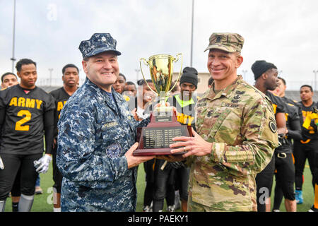 TACOMA, Wash. (Nov. 18, 2016) Cmdr. Anthony Pecoraro, Naval Base Kitsap’s executive officer, and Joint Base Lewis-McChord Command Sgt. Maj. Michael Grinston, hold the trophy at the conclusion of the 17th Annual Army/Navy Flag Football Game. The annual game has been a tradition since 2000 and it increases the morale and welfare of both Navy and Army personnel. Navy won the game 28-0. Stock Photo