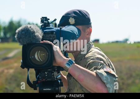 Sgt. Gary Kendall, a British Army Photographer with the Army News Team awaits the passing of the U.S. Air Force C-17 Globemaster III aircraft which will be releasing equipment and paratroopers at the air drop event as part of Exercise Anakonda 2016 in Torun, Poland, June 6, 2016. Exercise Anakonda 2016 is a Polish-led, joint, multinational exercise taking place in Poland from June 7-17. Large scale exercises such as Exercise Anakonda 2016 send a clear message that the United States and partner nations are capable of uniting and working together for collective defense. Stock Photo