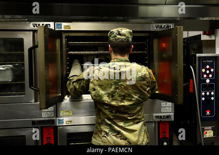 U.S. Army Pfc. Matthew Brokaw, U.S. Army Central Command culinary specialist, places a beef brisket into an oven at Shaw Air Force Base, S.C., March 17, 2016. The Chief Master Sgt. Emerson E. Williams Dining Facility staff spend close to three hours every day preparing lunch. (U.S. Air Force photo by Airman 1st Class Destinee Dougherty) Stock Photo