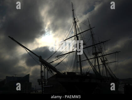 The sun breaks through the morning gloom to illuminate the USS Constellation at dock on the Baltimore Harbor during a Defense Information School photojournalism exercise March 4, 2016, Baltimore, MD. The USS Constellation, built in 1894, was the last sail-only warship designed and built by the United States Navy. Stock Photo