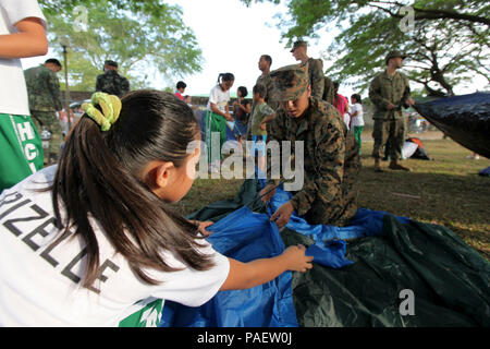 Lance Cpl. Estefania J. Patino, a field wireman, 31st Marine Expeditionary Unit and native of Dallas, Texas, helps Filipino schoolchildren assemble tents for a Boy/Girl Scout camping night during a visit to the Hanniel Christian Academy and Orphanage, Oct. 11. The visit was part of Amphibious Landing Exercise, a bilateral training exercise between U.S. and Philippine armed forces intended to increase interoperability and strengthen the bond between nations. PHIBLE', now in its 29th iteration, is an annually-scheduled exercise between the U.S. and Philippine forces, aimed at strengthening milit Stock Photo