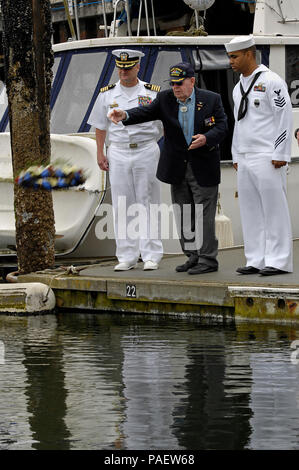 Oak Harbor, Wash. (June 4, 2012) Capt. Jay Johnston, left, commanding officer of Naval Air Station Whidbey Island, Cmdr. (ret.) Harry Ferrier, a Battle of Midway veteran, and Master-at-Arms 1st Class Adam Dickson, assigned to the base security, throw a wreath during a ceremony to commemorate the 70th Anniversary of the Battle of Midway. The Battle of Midway was the turning point in the Pacific War during World War II. Stock Photo