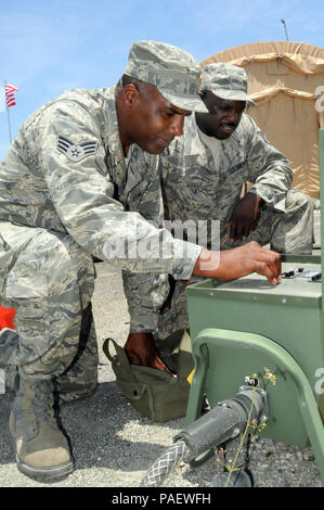 GUANTANAMO BAY, Cuba – U.S. Air Force Senior Airman William Shadd (left) and Air Force Staff Sgt. Cory Hodge (right), with the 474th Expeditionary Civil Engineering Squadron, repair a power source at Camp Justice, July 29, 2010. The 474th ECES supports Joint Task Force Guantanamo by maintaining the Expeditionary Legal Complex and Camp Justice facilities and infrastructure. JTF Guantanamo provides safe, humane, legal and transparent care and custody of detainees, including those convicted by military commission and those ordered released by a court. The JTF conducts intelligence collection, ana Stock Photo