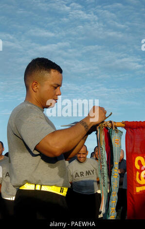 A Trooper attached to the 525th Military Police Battalion, places a streamer on the battalion's guidon for excellence in training, after a command run around Joint Task Force Guantanamo here, August 4, 2008. The 525th MP Battalion provides much of the guard force inside the JTF's detention facilities. JTF Guantanamo conducts safe and humane care and custody of detained enemy combatants. The JTF conducts interrogation operations to collect strategic intelligence in support of the Global War on Terror and supports law enforcement and war crimes investigations. JTF Guantanamo is committed to the  Stock Photo