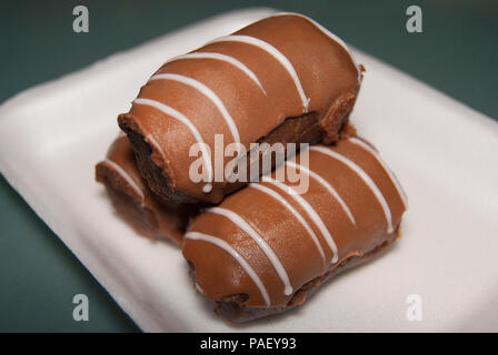 Three "Kartoshka" cakes lie on top of each other on a white rectangular plate. Side view. Stock Photo