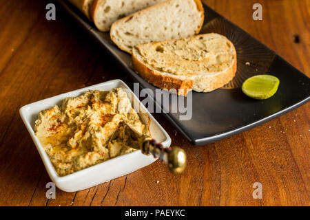 Hummus with sourdough bread on wooden jarrah board Stock Photo