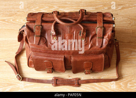 Brown leather travel bag or valise on wooden floor. Stock Photo