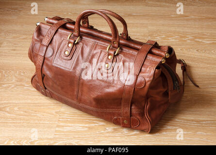 Brown leather travel bag or valise on wooden floor. Stock Photo