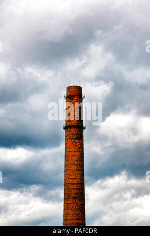 Old brick industrial chimney surrounded by a dramatic sky Stock Photo