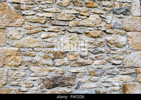 Fragment of a fortified wall made of stones of different types and cemented with cement mortar Stock Photo