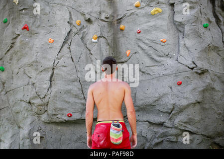 Photo from back of male climber on background of boulder for rock climbing during day Stock Photo
