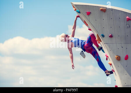 Picture from side of sports girl climbing on rocky summer day Stock Photo