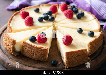 Classic plain New York Cheesecake with fresh berries sliced on wooden board, closeup view, selective focus Stock Photo